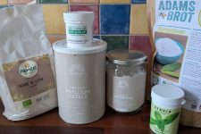 A bunch of keto ingredients on the kitchen counter. From left to right: lupin flour, gelatine powder, psyllium husk, erythritol, stevia, and bamboo fiber.